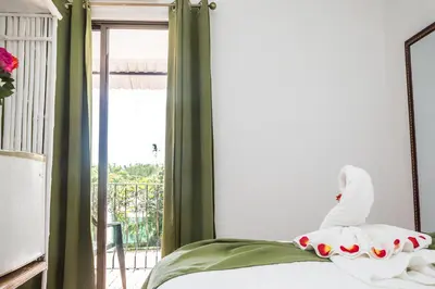 a bedroom with a bed with green curtains and a window at The Palms At Coco Beach in Coco