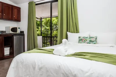 a bedroom with a white bed with green curtains at The Palms At Coco Beach in Coco