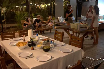 a table with plates of food and people on a patio at Pachamama Bungalows & Surfcamp - Santa Teresa in Carmen