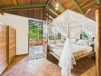 a bedroom with a bed with a mosquito net at Pachamama Bungalows & Surfcamp - Santa Teresa in Carmen