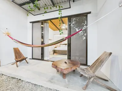 a room with a hammock and two chairs and a table at Pachamama Bungalows & Surfcamp - Santa Teresa in Carmen