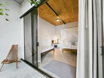 a room with a bed and a glass window at Pachamama Bungalows & Surfcamp - Santa Teresa in Carmen