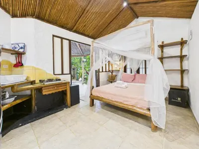a bedroom with a canopy bed and a desk at Pachamama Bungalows & Surfcamp - Santa Teresa in Carmen