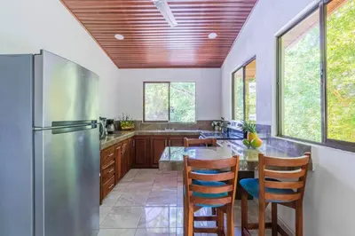 a kitchen with a stainless steel refrigerator and wooden cabinets at Tropical House in Nosara- 3 min walk to the beach in Río Seco