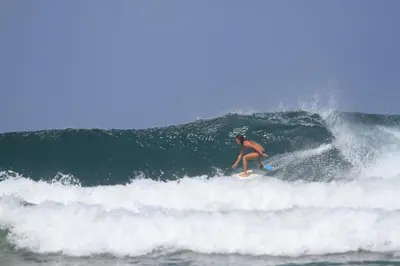 a man riding a wave on a surfboard in the ocean at Tropical House in Nosara- 3 min walk to the beach in Río Seco