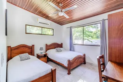 two beds in a room with a ceiling fan at Tropical House in Nosara- 3 min walk to the beach in Río Seco
