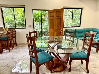 a dining room with a glass table and chairs at Tropical House in Nosara- 3 min walk to the beach in Río Seco