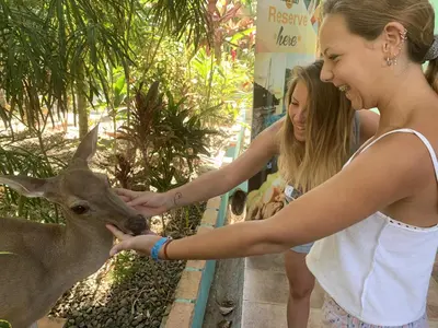 two girls petting a deer at a zoo at La Posada Jungle Hotel in Manuel Antonio