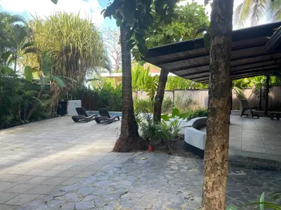 a patio with two palm trees and a bench at Beach Villa S in Santa Teresa Beach