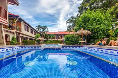 a pool at a hotel with two people sitting next to it at Hotel Mar de Luz in Jacó