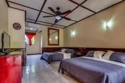 a bedroom with two beds and a ceiling fan at Hotel Mar de Luz in Jacó