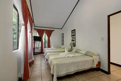 two beds in a room with white walls at Hotel Mar de Luz in Jacó