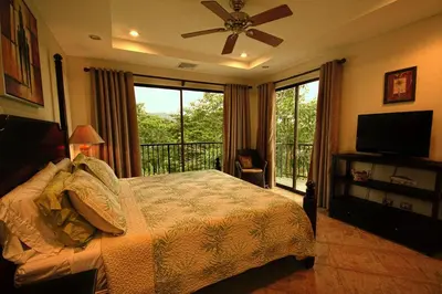a bedroom with a bed and a television and a balcony at Monaco Condominiums in Jacó
