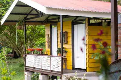 a yellow house with a white door and a porch at Poponé Farm & Lodge in Guápiles