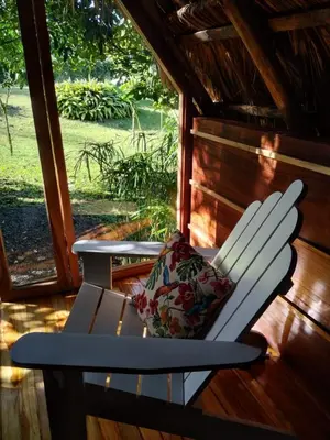 a white chair with a pillow sitting on a porch at Poponé Farm & Lodge in Guápiles