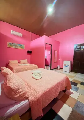a pink bedroom with two beds in a room at Hotel Sunset Rooms in Tortuguero