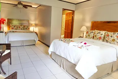 a hotel room with two beds and a table at Hotel Playa Espadilla & Gardens in Manuel Antonio