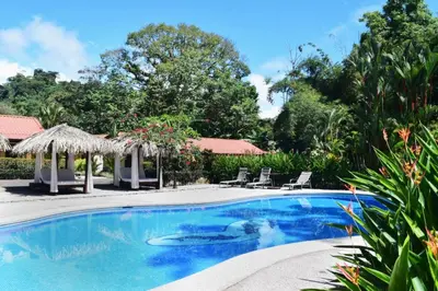 a swimming pool in a yard with chairs and umbrellas at Hotel Playa Espadilla & Gardens in Manuel Antonio
