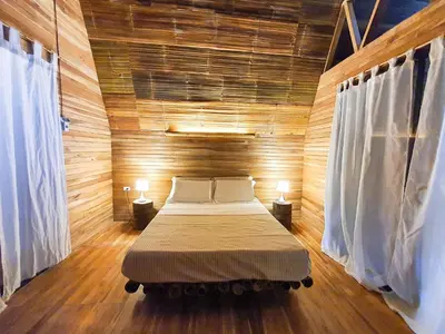 a bedroom with a bed in a wooden room at Buena Onda Bungalows in Santa Teresa Beach