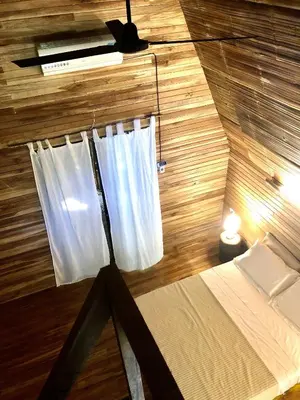 a room with a bed with a white curtain at Buena Onda Bungalows in Santa Teresa Beach