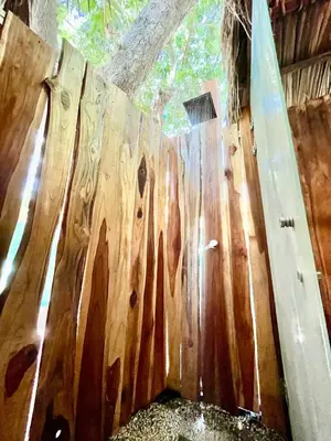 a wooden fence with a surfboard leaning against it at Buena Onda Bungalows in Santa Teresa Beach