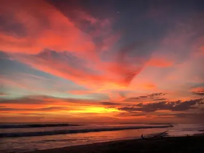 a sunset on a beach with the ocean at Buena Onda Bungalows in Santa Teresa Beach