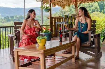 two women sitting at a table with glasses of wine at Ladera Hotel in Turrialba