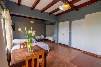 a room with two beds and a table with flowers on it at Ladera Hotel in Turrialba