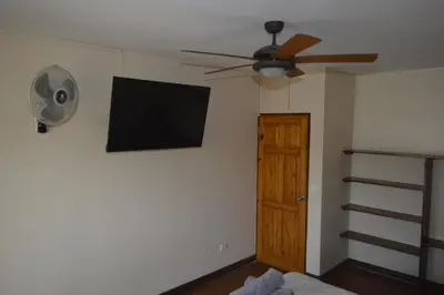 a ceiling fan and a flat screen tv on a wall at Apartotel VILLA ALTA TAMARINDO in Tamarindo
