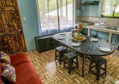 a living room with a table and chairs and a kitchen at Cabañas Río Escondido en La Fortuna in Fortuna