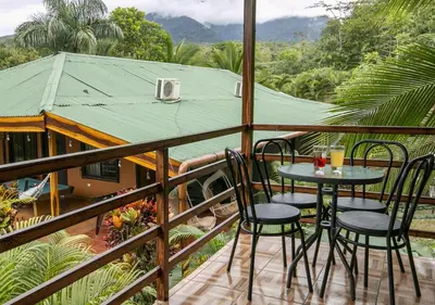 a balcony with a table and chairs and a house at Cabañas Río Escondido en La Fortuna in Fortuna