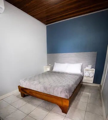 a bedroom with a bed with a blue wall at Arenal Poshpacker Boutique Urban Tropical Hotel in Fortuna