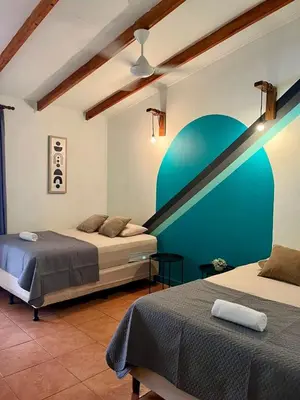 a bedroom with two beds and a blue wall at Point Break Santa Teresa in Santa Teresa Beach