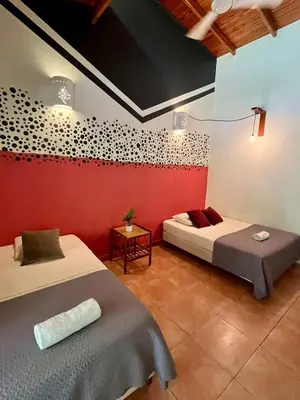 a bedroom with two beds and a red wall at Point Break Santa Teresa in Santa Teresa Beach