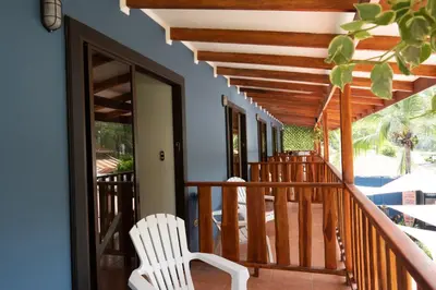 a wooden balcony with a white chair on a porch at Point Break Santa Teresa in Santa Teresa Beach