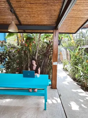 a woman sitting on a blue bench with a laptop at Point Break Santa Teresa in Santa Teresa Beach
