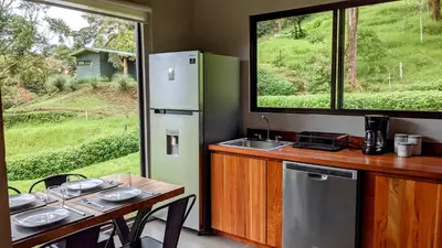 a kitchen with a table and a refrigerator at Olingo Monteverde - Stunning Home Near Adventure Parks in Monteverde Costa Rica