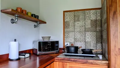 a kitchen with a microwave and a stove with pots and pans at Olingo Monteverde - Stunning Home Near Adventure Parks in Monteverde Costa Rica