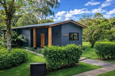 a small blue house in a garden at Olingo Monteverde - Stunning Home Near Adventure Parks in Monteverde Costa Rica