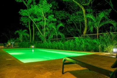a swimming pool at night with a table and trees at Casa Coco de Mer 1 in Tamarindo