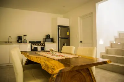 a kitchen with a wooden table with chairs and a kitchen with stairs at Casa Coco de Mer 2 in Tamarindo