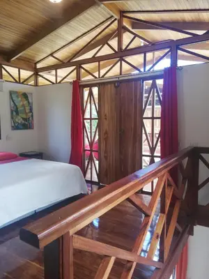 a bedroom with a bed and a wooden staircase at Ibiza Tropical Beach Villas in Uvita
