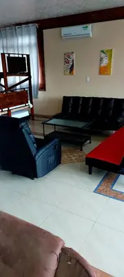 a living room with a black couch and a red rug at El Castillo Monte Campana in Puntarenas