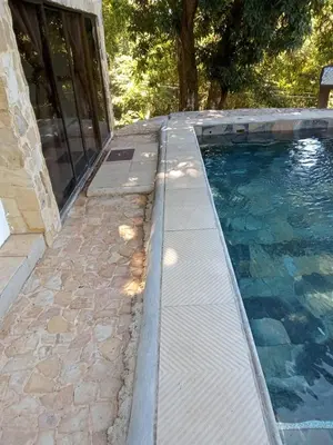 a swimming pool with a stone walkway next to the water at El Castillo Monte Campana in Puntarenas