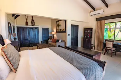 a bedroom with a large bed and a living room at Sunset del Mar Beach Resort in Esterillos Este