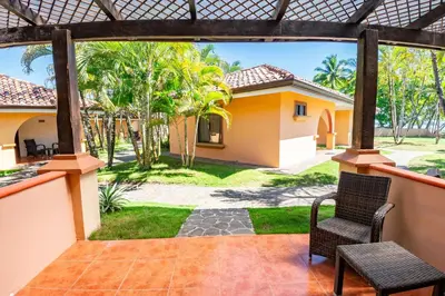 a patio with two chairs and a house at Sunset del Mar Beach Resort in Esterillos Este
