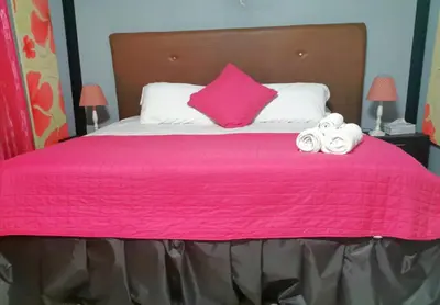 a pink bed with two towels and a pink pillow at CHEZ NOUS in Carrillo