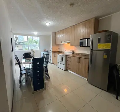 a kitchen with a table and a stainless steel refrigerator at Casa apartamento Costa Linda jaco in Jacó