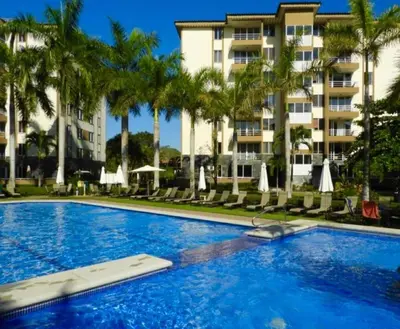 a swimming pool with palm trees and a building at Casa apartamento Costa Linda jaco in Jacó