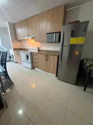 a kitchen with a stainless steel refrigerator and wooden cabinets at Casa apartamento Costa Linda jaco in Jacó